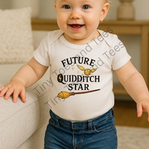 May include: A smiling baby wearing a white onesie with the words "Future Quidditch Star" and a golden snitch and broom graphic. The baby is also wearing blue jeans.