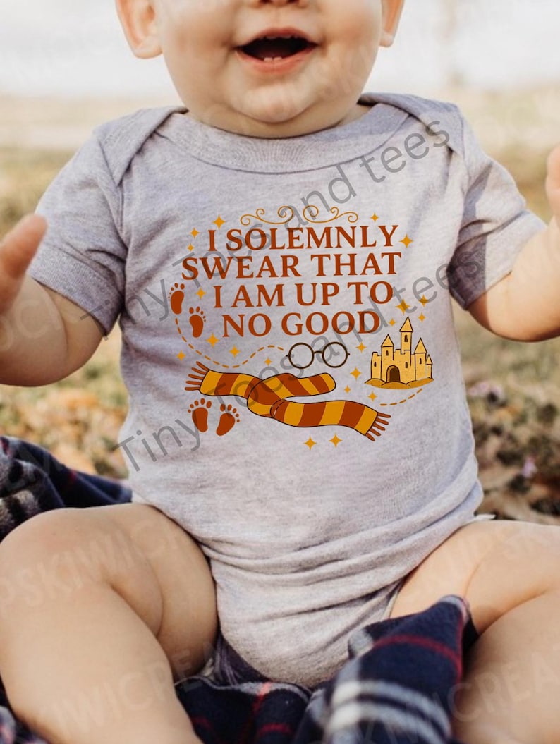 May include: A gray baby onesie with the text "I SOLEMNLY SWEAR THAT I AM UP TO NO GOOD" in brown and orange. The design includes a scarf, glasses, castle, and footprints.