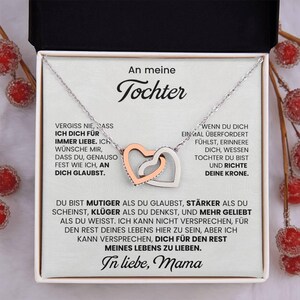 May include: A silver necklace with two interlocking heart pendants, one rose gold and one silver, presented in a gift box. The box contains a message in German, addressed to "Tochter" (daughter), with an inspirational message.