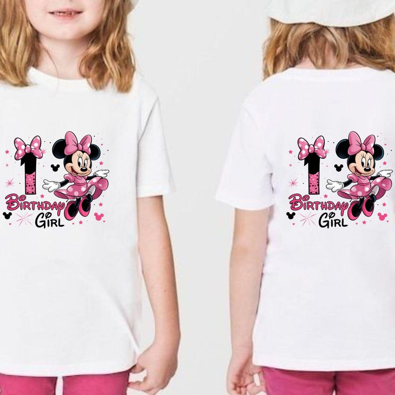 May include: White t-shirts with a colourful graphic featuring Minnie Mouse in a pink dress, the number 1, and the text "Birthday Girl." The design includes pink bows and stars. The shirts are for a young girl.