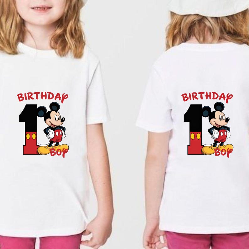 May include: White t-shirts with a colorful graphic featuring Mickey Mouse, the number 1, and the word "Birthday Boy". The graphic is in red, black, yellow, and white. The shirts are for a child's first birthday.