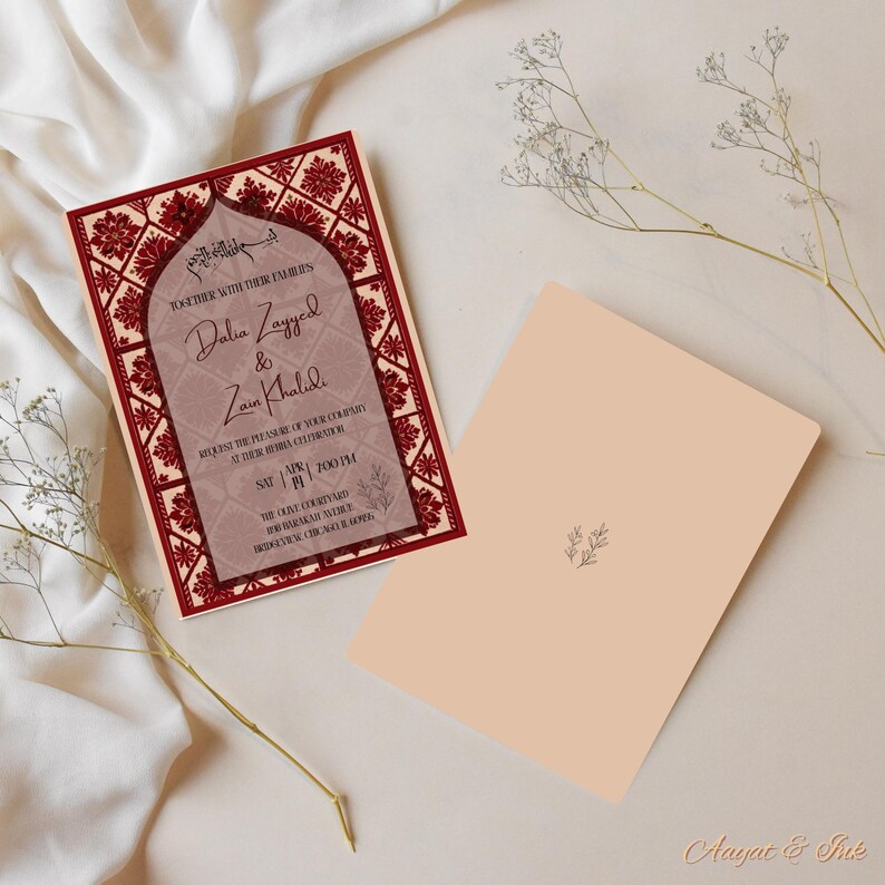 May include: A wedding invitation with a burgundy and cream color scheme. The invitation features ornate floral patterns and the names "Dalia Zayyed & Zain Khalidi". The back of the invitation is a solid cream color with a small floral design.
