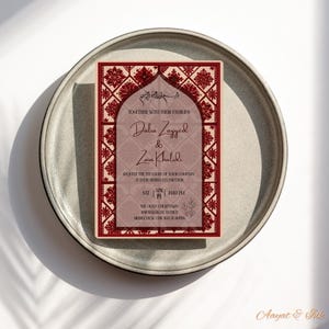 May include: A rectangular invitation card with a burgundy and cream color scheme, featuring floral and geometric patterns. The card includes names, event details, and the phrase "Together with their families."