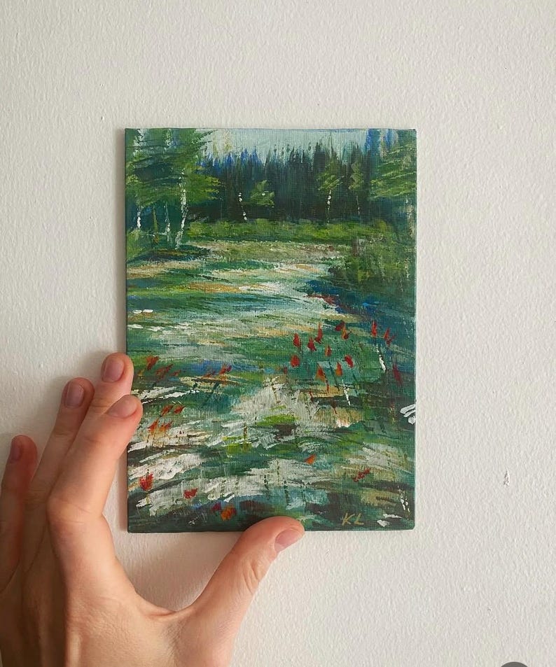 May include: An original landscape painting depicting a forest scene with a stream and red flowers. The artwork is painted with green, blue, and white brushstrokes. The painting is held by a hand against a white wall.
