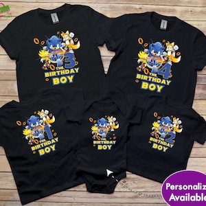 May include: Black t-shirts and a onesie featuring Sonic the Hedgehog and the text "The Birthday Boy" with the numbers 1, 2, 3, and 4. The design includes Sonic, Tails, and other characters.