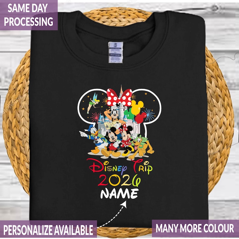 Pode incluir: Camisola preta com um design colorido Disney Trip 2020 com Mickey Mouse, Minnie Mouse, Pato Donald e outros personagens. O design inclui um contorno da cabe&ccedil;a do Mickey Mouse e a palavra "NAME" abaixo.