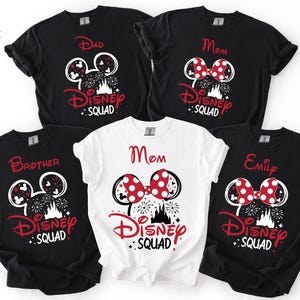 Puede incluir: Una colecci&oacute;n de camisetas negras y blancas de Disney Squad con detalles en rojo. Las camisetas presentan orejas de Mickey Mouse, fuegos artificiales y los nombres "Dad", "Mom", "Brother" y "Emily". Una camiseta blanca tambi&eacute;n dice "Mom".