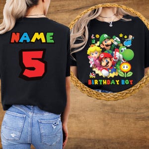 May include: Black t-shirt with a colourful graphic of Mario, Luigi, Princess Peach, Yoshi, and other characters. The shirt also has the text "BIRTHDAY BOY". The back of the shirt has the word "NAME" and the number "5".