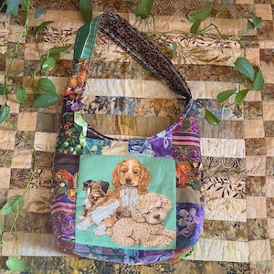 May include: A patchwork shoulder bag with a green strap and a brown patterned handle. The bag features a central square with a print of three puppies. The bag's fabric is a mix of floral and patterned designs.