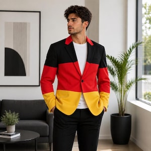 May include: A black, red, and yellow blazer with a single-button closure. The blazer's design features horizontal stripes in the colors of the German flag. The person is wearing a white t-shirt and black pants.
