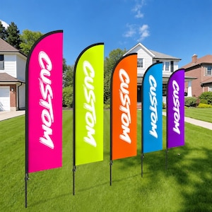 May include: Five colorful feather flags with the word "CUSTOM" in white script. The flags are in shades of pink, lime green, orange, blue, and purple, and are displayed on a green lawn in front of houses.