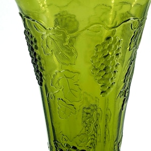 Op de afbeelding: Groene glazen vaas met een reli&euml;f van druiven en bladeren. De vaas heeft een uitlopende bovenkant en een ronde basis. Het druivenpatroon herhaalt zich rond de vaas. Het glas heeft een getextureerd oppervlak.