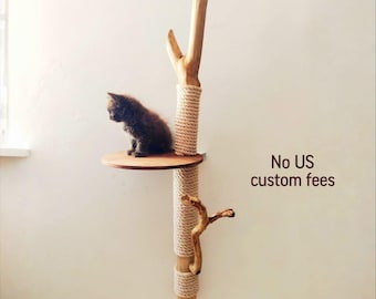 May include: A wall-mounted cat tree with a small, dark-furred kitten sitting on a round wooden platform. The tree is made of natural wood, rope, and branches. The text "No US custom fees" is visible.