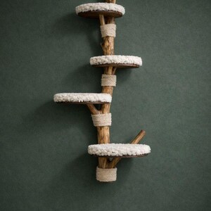 May include: A wooden cat tree with four circular platforms covered in white, fluffy material. The platforms are attached to a central wooden structure wrapped with natural rope. The cat tree is designed to be mounted on a wall.