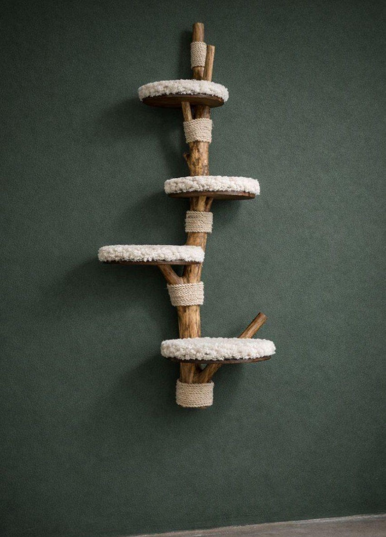 May include: A wooden cat tree with four circular platforms covered in white, fluffy material. The platforms are attached to a central wooden structure wrapped with natural rope. The cat tree is designed to be mounted on a wall.