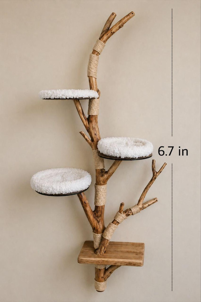 May include: A wall-mounted cat tree featuring a natural wood branch structure with three circular platforms topped with white plush cushions. The branch is wrapped with tan rope at various joints. A small section measures 17.02 cm in height.