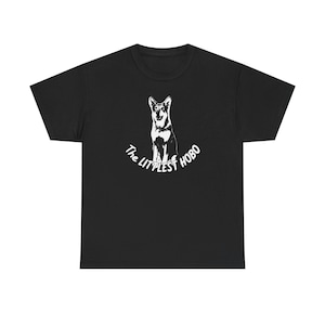 May include: Black t-shirt featuring a white graphic of a dog with the text "The Littlest Hobo" in a curved font. The dog illustration is detailed, showing the dog's features. The shirt is made of a soft material.