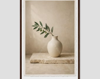 May include: A framed wall art print featuring a smooth, off-white ceramic vase resting on a rectangular, rough-hewn stone block. A single green olive branch with small leaves and olives extends from the vase against a neutral beige background.