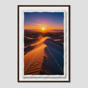May include: A framed vertical print featuring a desert landscape at sunset with rolling sand dunes. The scene displays a gradient from deep blue at the top to bright orange and gold at the horizon. The text Maple & Marker Copyright is visible.