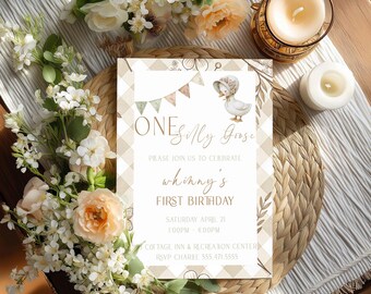 May include: A birthday invitation with the text "ONESilly Goose" and "whinny's FIRST BIRTHDAY". The invitation features a gingham pattern, a banner, and a cartoon goose wearing a bonnet. The invitation is surrounded by flowers and candles.
