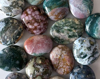 Könnte beinhalten: Eine Sammlung polierter Edelsteine in verschiedenen Farben, darunter Grün, Braun, Rosa und Blau. Die Steine weisen einzigartige Muster und Texturen auf und haben eine glatte, abgerundete Form. Diese Natursteine eignen sich ideal für die Schmuckherstellung oder das Sammeln.