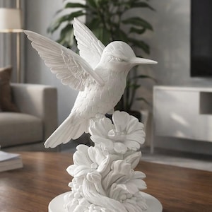 May include: A white hummingbird sculpture with outstretched wings, perched on stylized flowers. The bird's detailed feathers and the floral base create a decorative accent. The sculpture is made of a solid, smooth material.