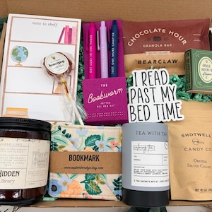 Puede incluir: Una caja de regalo que contiene un bloc de notas, una piruleta, un juego de tres bol&iacute;grafos de gel, una barrita de cereales, una caja verde peque&ntilde;a, una pegatina con el texto I READ PAST MY BED TIME, una vela, un marcap&aacute;ginas floral, t&eacute; y caramelos.