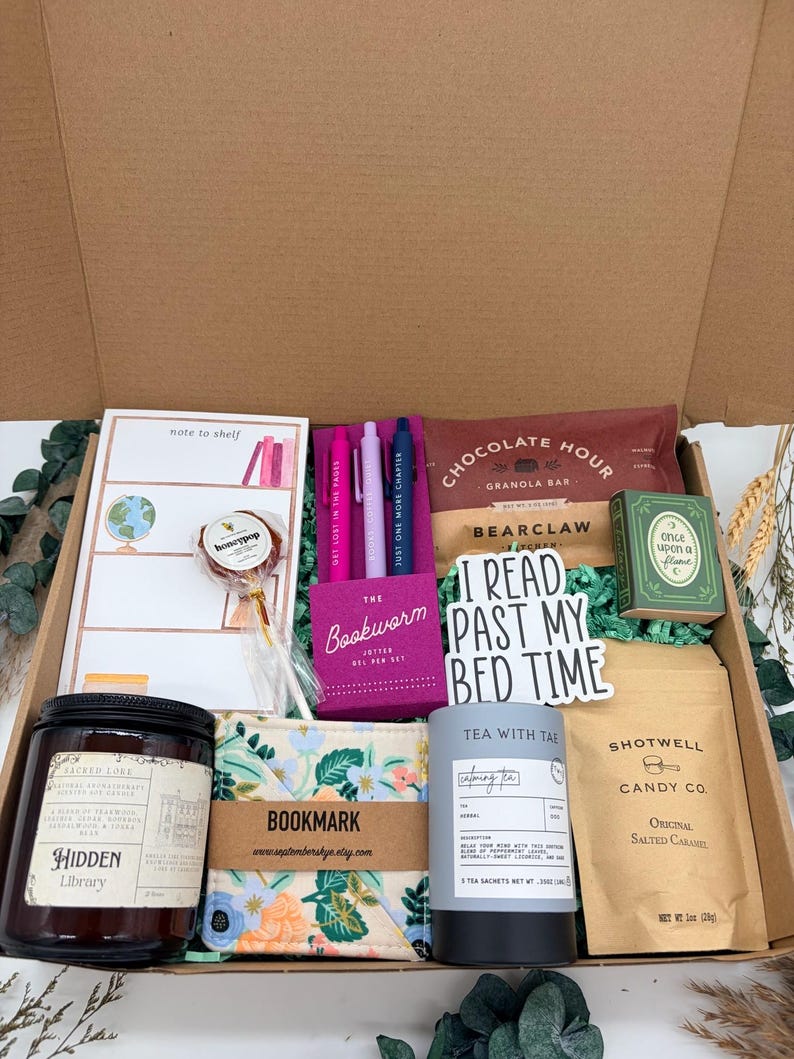 Puede incluir: Una caja de regalo con un bloc de notas, una piruleta, tres bol&iacute;grafos de gel, una barrita de cereales, una caja verde, una pegatina que dice I READ PAST MY BED TIME, una vela Hidden Library, un marcap&aacute;ginas de tela floral, t&eacute; y caramelos.