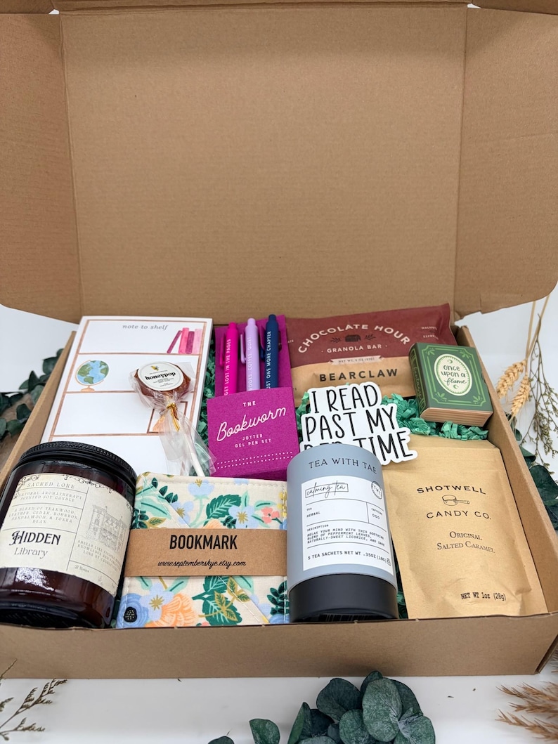 Puede incluir: Una caja de regalo de cart&oacute;n que contiene una vela Hidden Library, un marcap&aacute;ginas floral, un bloc de notas, tres bol&iacute;grafos de gel, una barrita de cereales Chocolate Hour, una cajita con forma de libro, t&eacute;, caramelos y una piruleta.