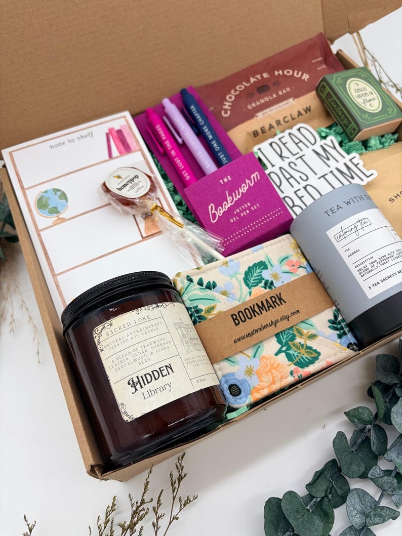 Puede incluir: Una caja de regalo que contiene una vela de soja Hidden Library, un marcap&aacute;ginas de tela floral, una lata de t&eacute; gris, un bloc de notas con la etiqueta note to shelf, tres bol&iacute;grafos de gel, una barrita de granola de chocolate y una piruleta.
