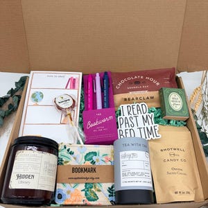 Puede incluir: Una caja de regalo que contiene un bloc de notas, una piruleta honeypop, un juego de bol&iacute;grafos de gel Bookworm, una barrita de cereales Chocolate Hour, un libro peque&ntilde;o verde, una vela Hidden Library, un marcap&aacute;ginas floral, t&eacute; y caramelos.