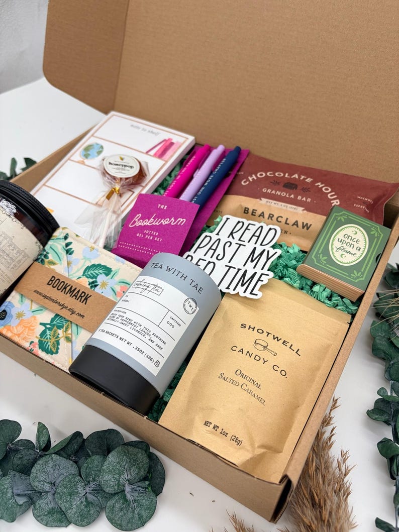 Puede incluir: Una caja de regalo que contiene un bote de t&eacute; Tea With Tae, una bolsa de caramelo salado Shotwell Candy Co., una barrita de granola Chocolate Hour, un set de bol&iacute;grafos de gel Bookworm, un marcap&aacute;ginas floral, una piruleta, una caja verde Once Upon a Flame y una pegatina con el texto I READ PAST MY BED TIME.