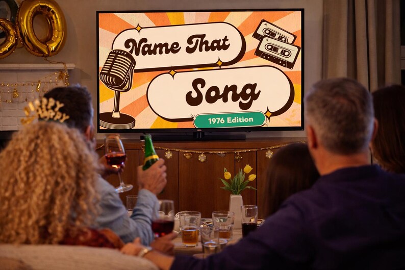 May include: A television screen displays the words "Name That Song" with a retro microphone and cassette tapes graphic. The text "1976 Edition" is also visible. People are gathered around, some holding drinks.