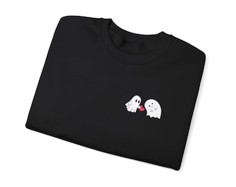 Puede incluir: Sudadera negra con un pequeño diseño bordado de dos fantasmas blancos sosteniendo un corazón rojo. La sudadera tiene cuello redondo y mangas largas. El diseño está en el pecho izquierdo.