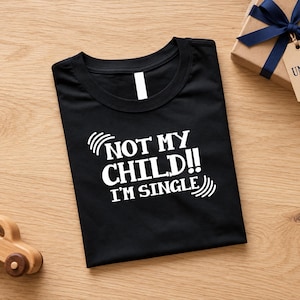 May include: A black short-sleeved t-shirt featuring white text that reads NOT MY CHILD!! I'M SINGLE with curved lines on the sides. The shirt has a round neckline and is folded flat, displaying the graphic clearly on the front center.