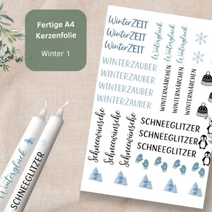 Könnte beinhalten: Zwei weiße Kerzen mit blauem Winter-Text und Grafiken, neben einem Bogen mit winterlichen Aufklebern. Die Aufkleber zeigen Schneeflocken, Mützen, Pinguine und Texte wie "Winter Zeit" und "Schneeglitzer".