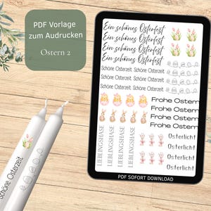 Könnte beinhalten: Ein digitales Tablet zeigt Ostermotive und Text, darunter "Ein schönes Osterfest" und "Frohe Ostern". Zwei weiße Kerzen mit Blumen- und Eierdesigns befinden sich links. Das Bild befindet sich auf einer Holzoberfläche.