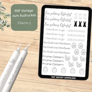 Könnte beinhalten: Ein digitales Oster-Themen-Download, angezeigt auf einem Tablet, mit Text und Grafiken. Zwei weiße Kerzen mit Text befinden sich im Vordergrund. Das Tablet zeigt Sätze wie "Ein schönes Osterfest" und Oster-bezogene Illustrationen.