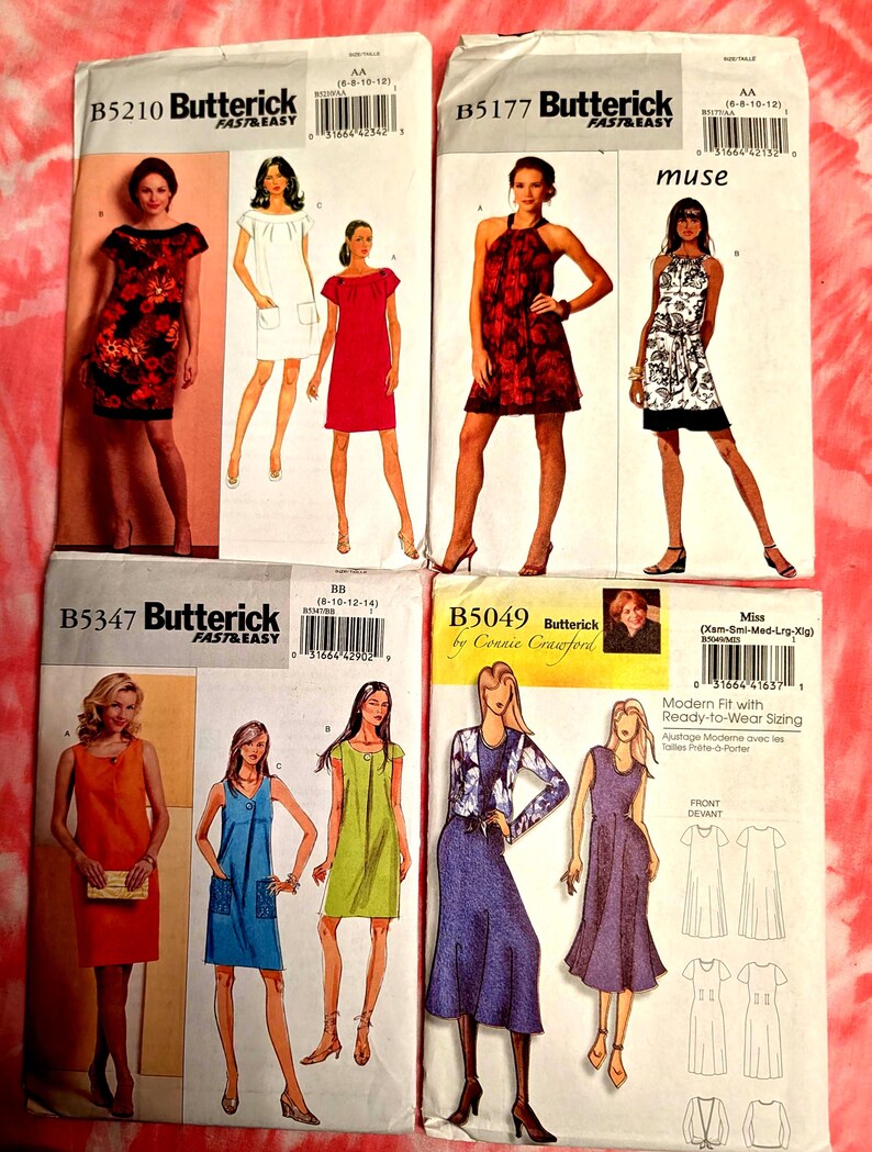 May include: Collection of Butterick sewing pattern envelopes featuring illustrations of dresses. The patterns showcase various dress styles, including a red floral print dress, a white dress with pockets, and a halter dress with a floral pattern. The envelopes are on a pink tie-dye background.