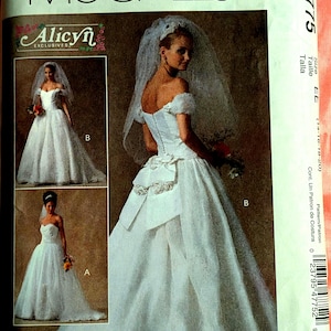 May include: A McCall's sewing pattern for a wedding dress. The pattern features a white bridal gown with a sweetheart neckline and a veil. The pattern includes multiple views of the dress, with the text "Alicyn Exclusives" visible.