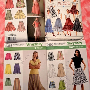 May include: Four Simplicity sewing pattern envelopes featuring skirt designs. The patterns showcase various skirt styles, including A-line, tiered, and wrap skirts. The envelopes display images of the finished garments and include sizing information.