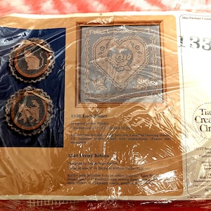 May include: A craft kit package featuring a framed lacy heart design and two small embroidered hoops with animal silhouettes. The package includes the text "1336 Lacy Heart" and "The Creative Circle" logo.