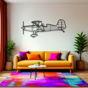 May include: A black metal airplane wall art decorates a white wall above a yellow sofa with colorful pillows. A vibrant, multi-colored rug and potted plants complete the room's decor. The airplane is a biplane design.