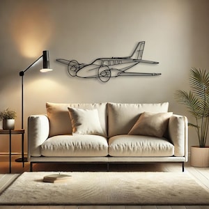 Op de afbeelding: Zwart metalen vliegtuig wandkunst. Het kunstwerk toont een tweemotorig vliegtuig met propellers, vleugels en een staart. De kunst is gemonteerd op een neutraal gekleurde muur boven een crèmekleurige bank.