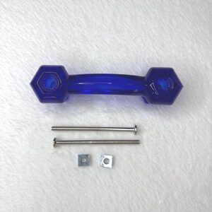 May include: A vibrant blue glass cabinet pull with a hexagonal design on each end. Includes two silver screws and two square nuts for installation. The pull is approximately 6 inches long.