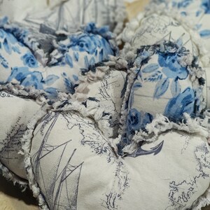 May include: A collection of heart-shaped fabric ornaments. The ornaments feature a mix of blue floral and nautical map patterns on a white background. Each heart has a frayed edge, adding a rustic touch. The overall aesthetic is vintage and romantic.