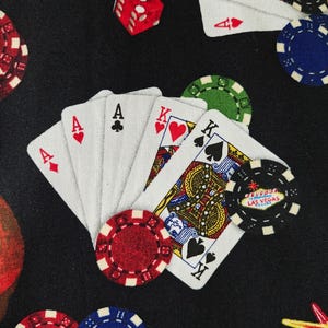 May include: A black background with playing cards, dice, and poker chips. The cards show the Ace of Diamonds, Ace of Spades, Ace of Hearts, and King of Hearts and Spades. Poker chips are red, green, and blue.