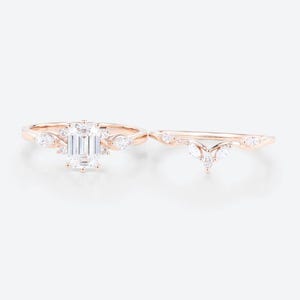 May include: Two rose gold rings. The first ring has a rectangular emerald-cut central stone, with smaller round and marquise-cut stones. The second ring is a curved band with marquise-cut and round stones, designed to complement the first ring.