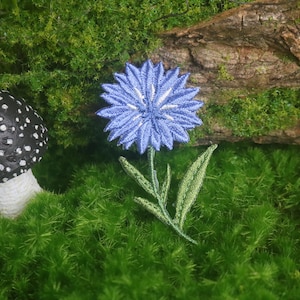 Pode incluir: Uma caneca de cerâmica branca com uma alça preta e o texto "But First, Coffee" em negrito preto. A caneca está cheia de um líquido escuro, provavelmente café, e está sobre uma superfície clara.