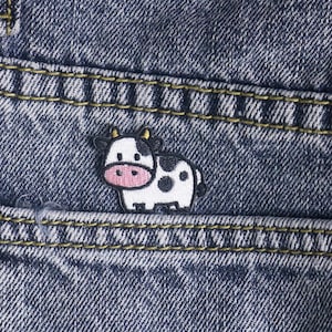 Puede incluir: Una taza de cerámica blanca con un asa negra y el texto "But First, Coffee" en negrita negra. La taza se encuentra sobre un fondo neutro, resaltando su diseño simple.